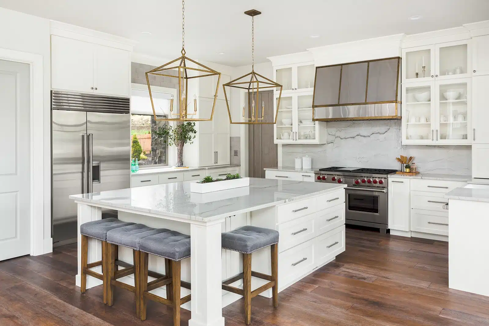 A luxurious kitchen featuring a large central island with comfortable seating and elegant pendant lights, highlighting the benefits of adding an island to the space