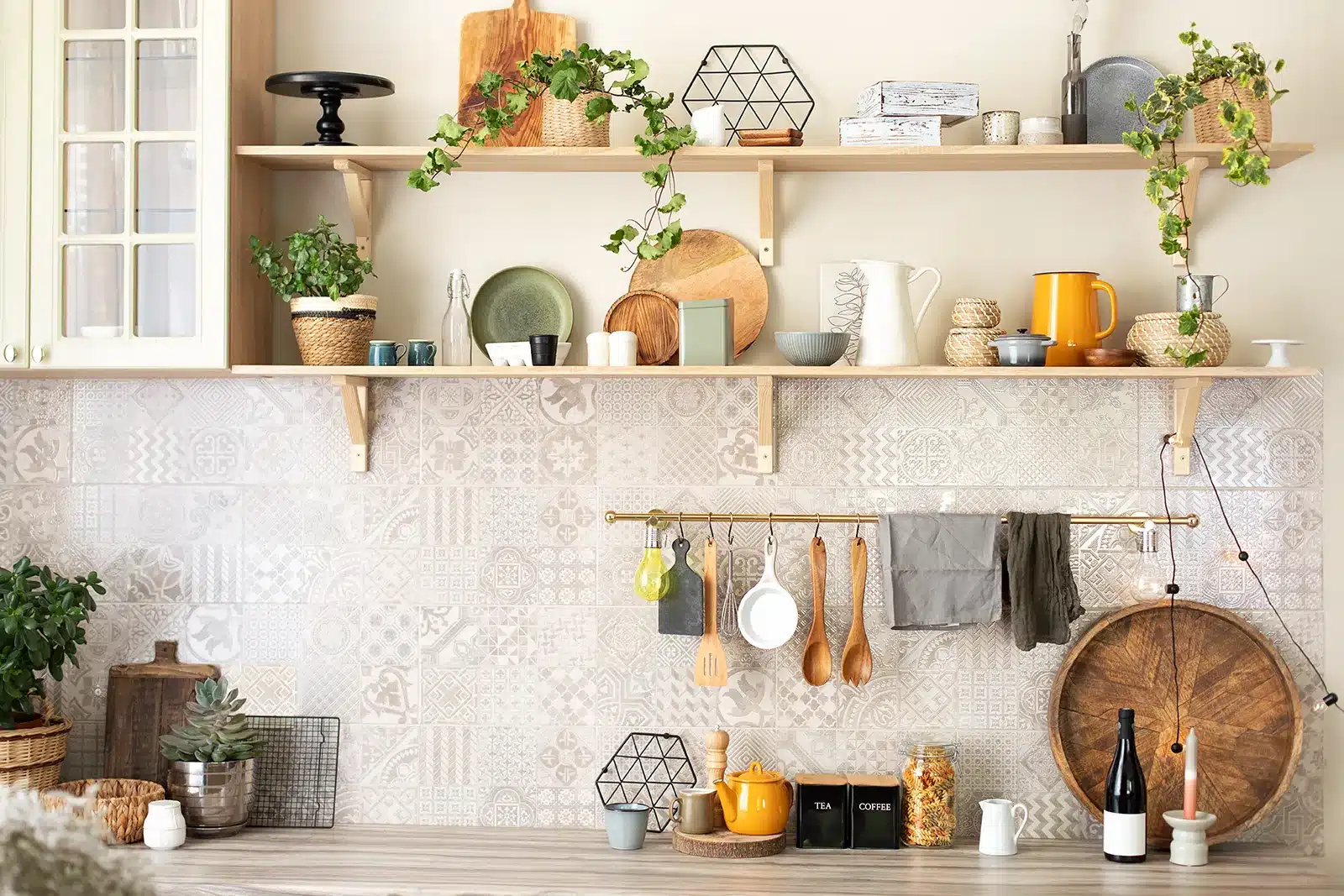 A kitchen's rustic charm is accentuated by a patterned tile backsplash, wooden shelves adorned with plants and kitchenware, and utensils hanging neatly below.
