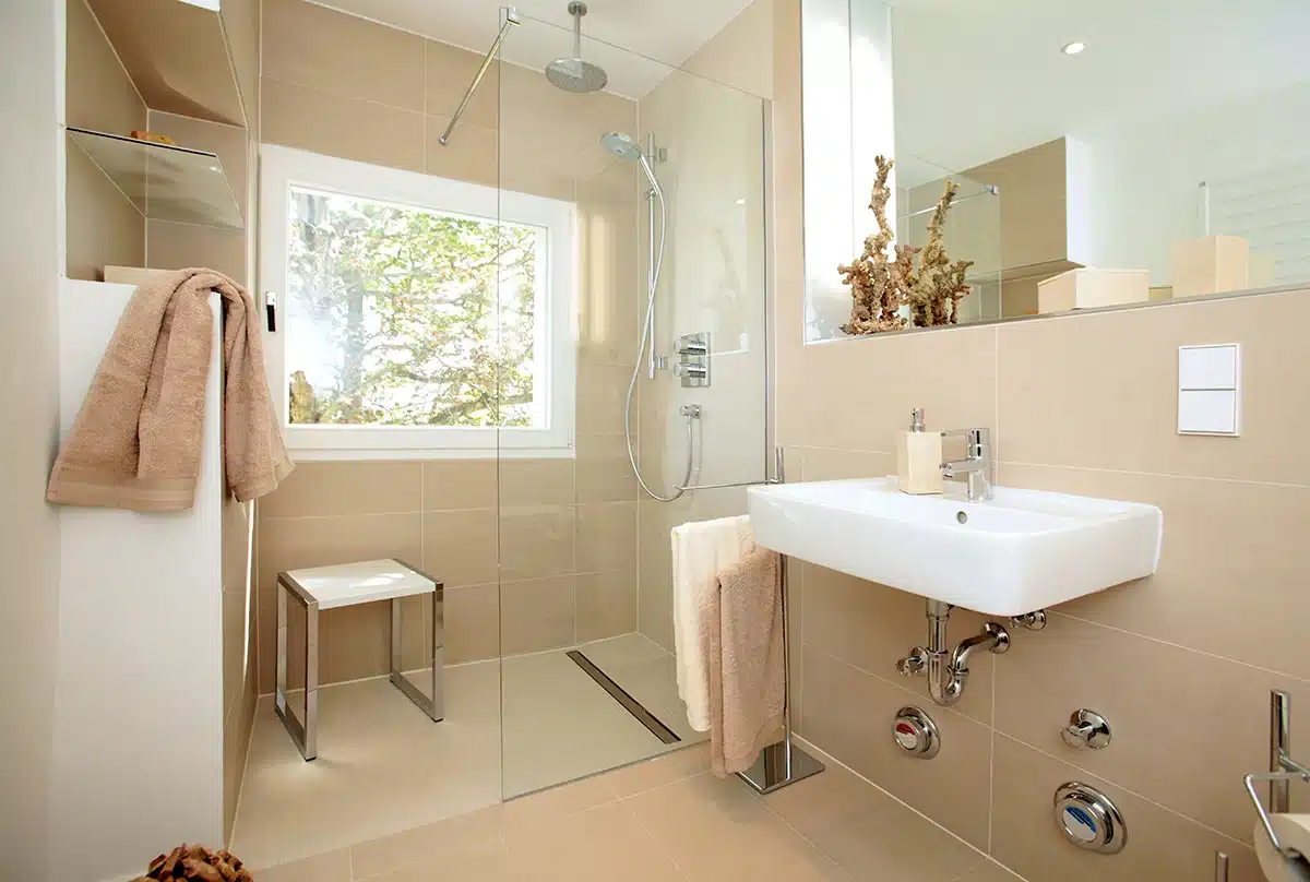 A curbless walk-in shower in a Seattle home, designed for accessibility with beige tiles and a clear glass door.