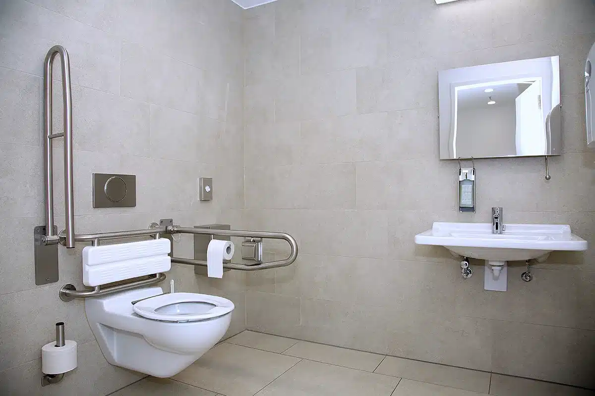 Modern accessible bathroom with wall-mounted toilet and safety handles in a Seattle home.