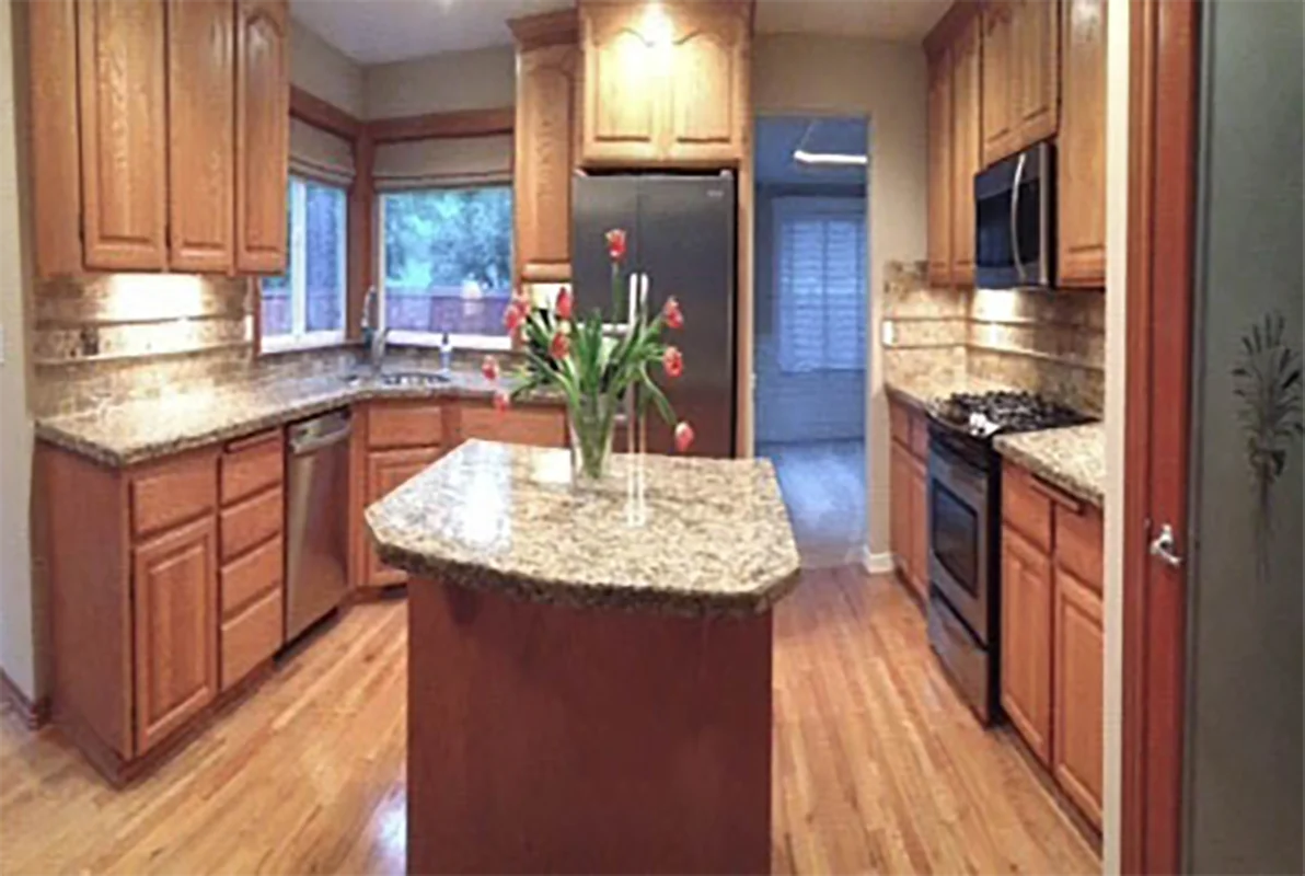 Before remodel with dated wooden cabinets and traditional granite countertops in Puyallup kitchen.