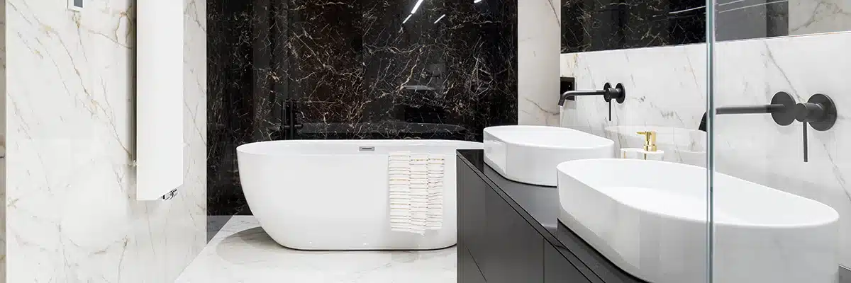 Elegant bathroom with a freestanding white bathtub, dual white basins on a black vanity, and contrasting black and white marble walls