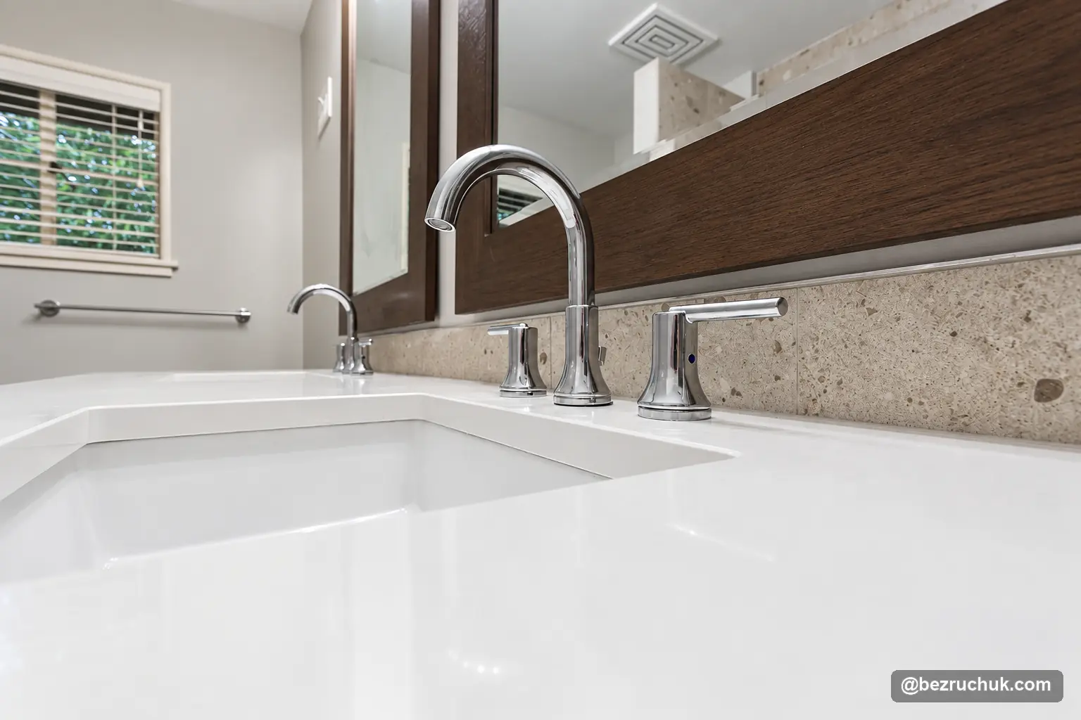 - project image Arched chrome faucet and lever handles over a white sink with a wood-framed mirror