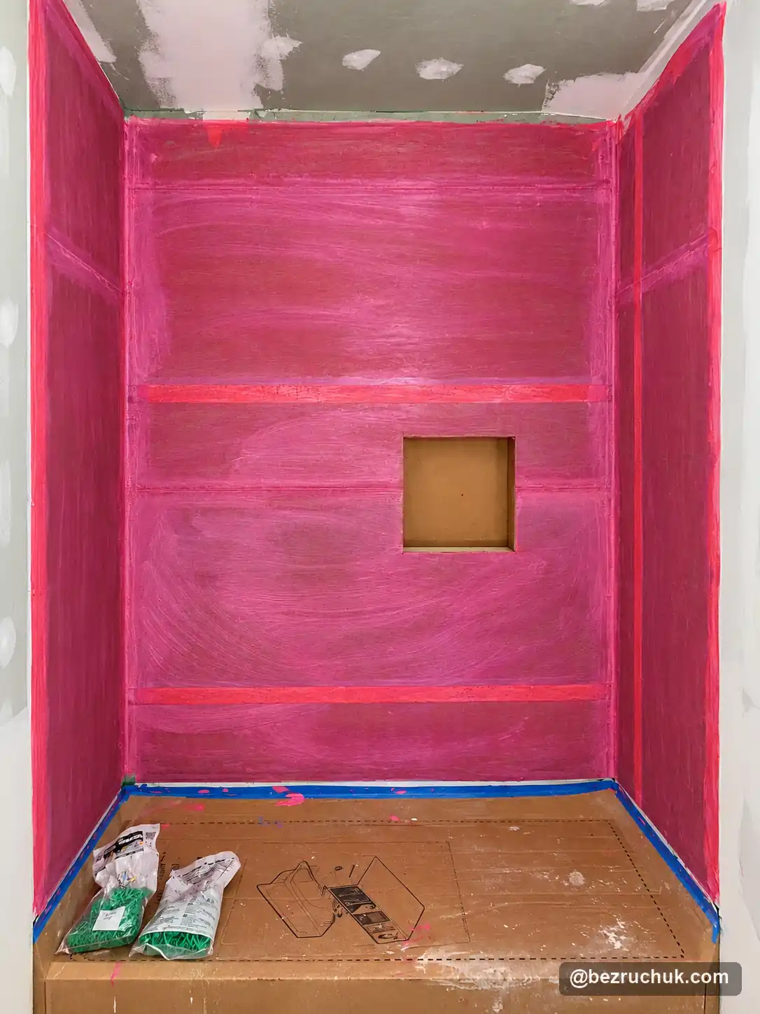 - project image Red waterproofing coating on the tub surround walls around a recessed niche