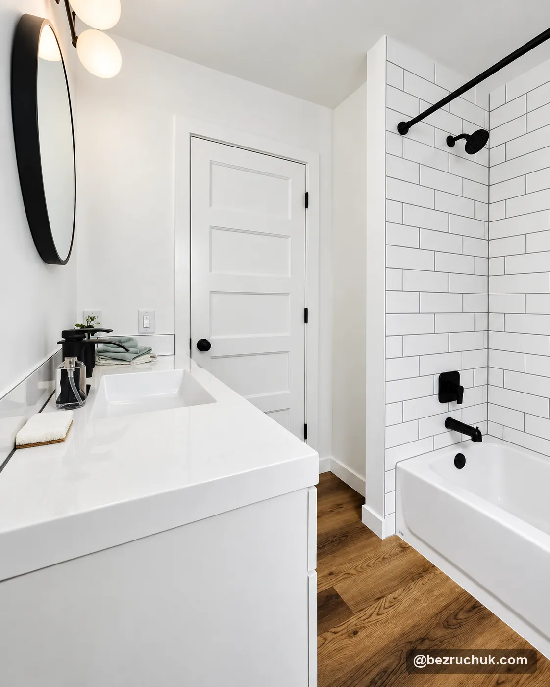 - project image White vanity and tiled bathtub with black fixtures in the completed bathroom