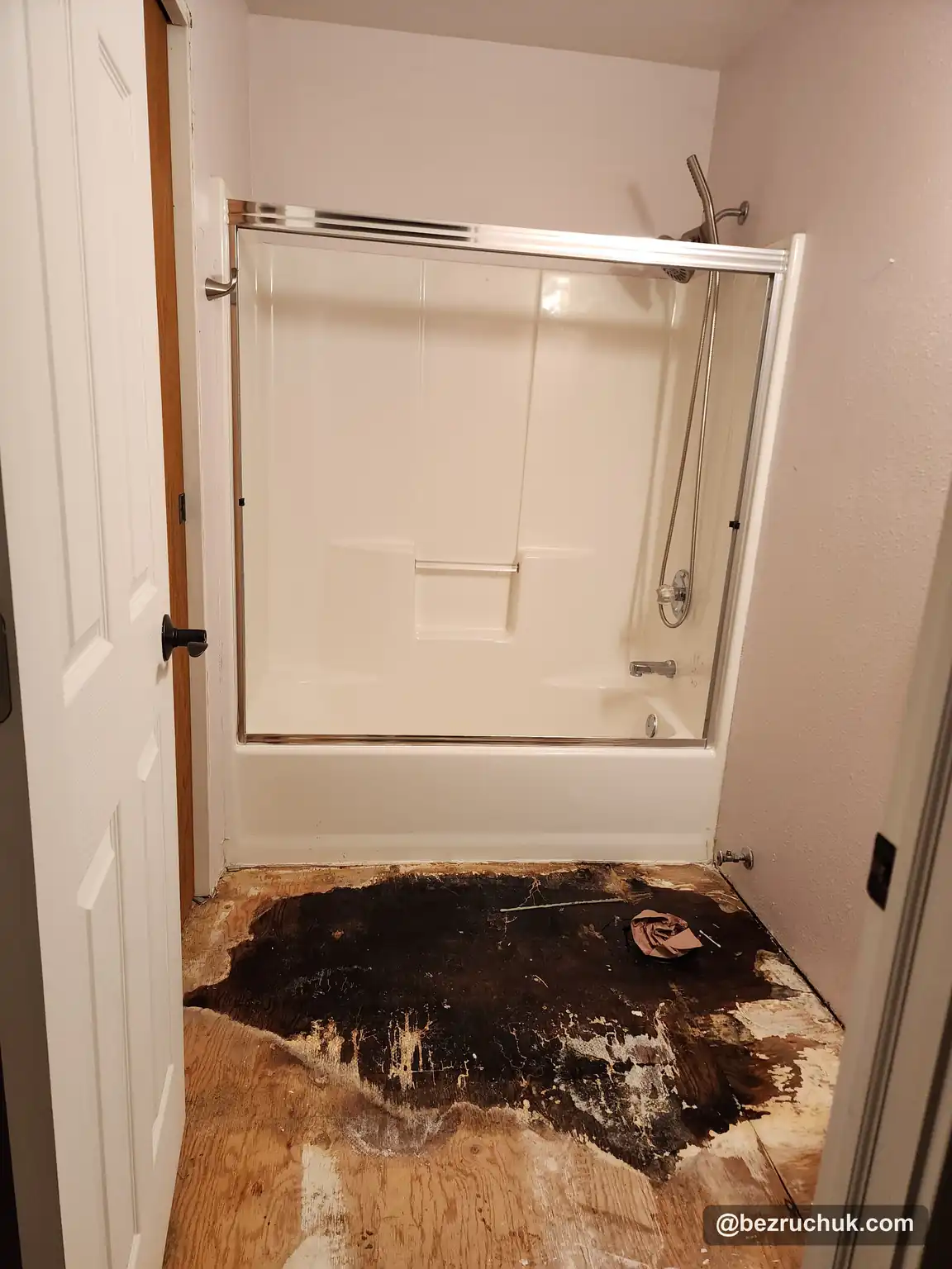 - project image Exposed stained and damaged bathroom subfloor beside the original tub