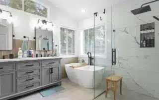 A luxurious bathroom with marble walls, a freestanding bathtub, and a spacious glass-enclosed shower.