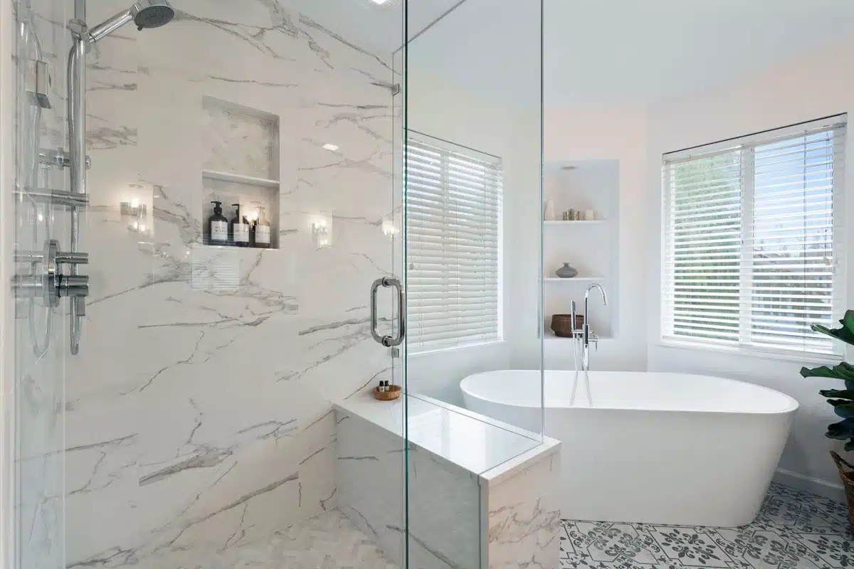 Spacious master bathroom with a freestanding tub, steam shower, and marble wall tiles.