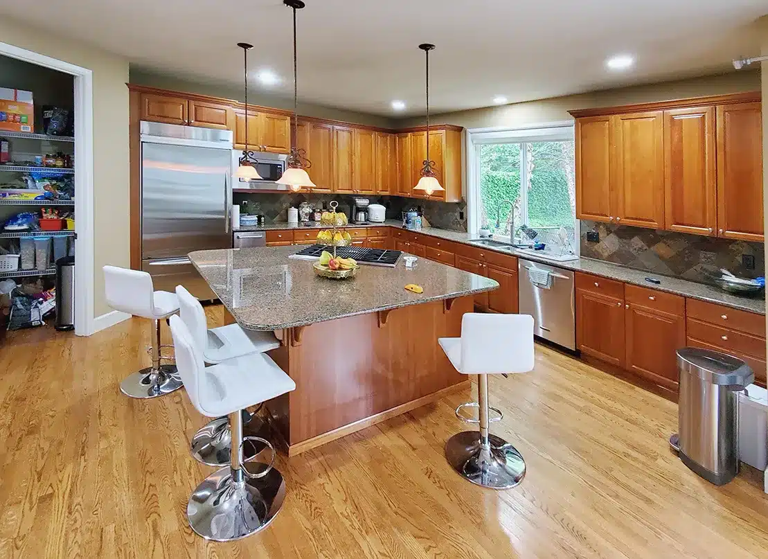 Traditional kitchen with wooden cabinets, granite countertops, and stainless steel appliances before remodeling.