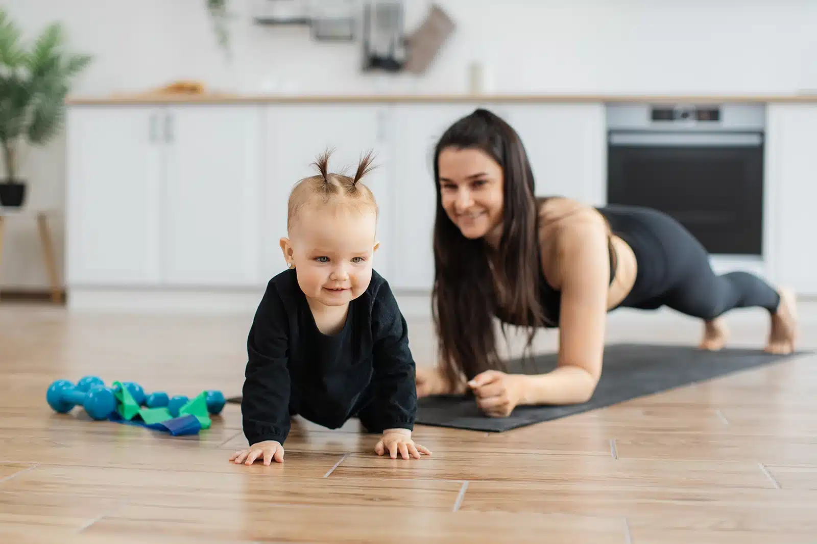 A young child and an adult engage in playful exercise on a durable wood-look kitchen floor in a Tacoma home, reflecting a family-friendly design.