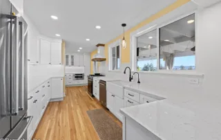 Edgewood kitchen renovation with white shaker cabinets, hardwood flooring, and pendant lighting.