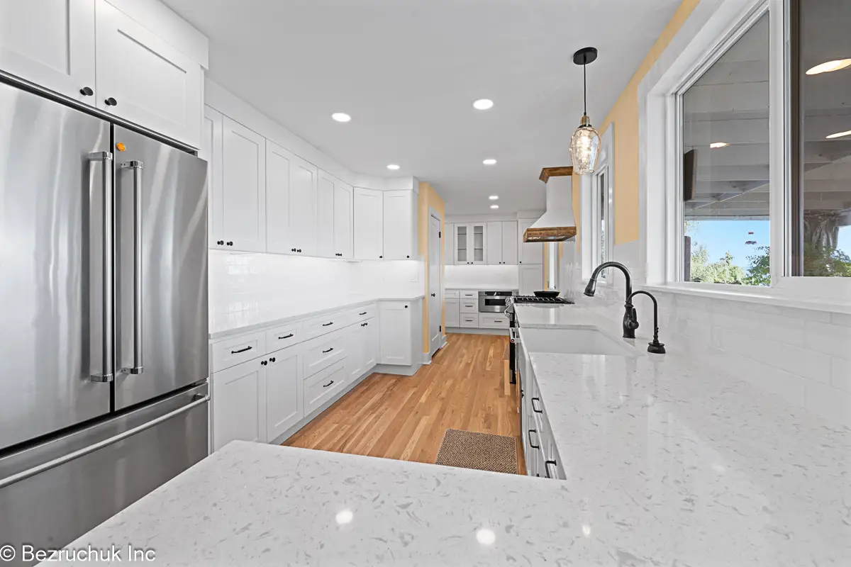 After photo of remodeled Edgewood kitchen with quartz counters, white shaker cabinets, farmhouse sink, and hardwood floors.