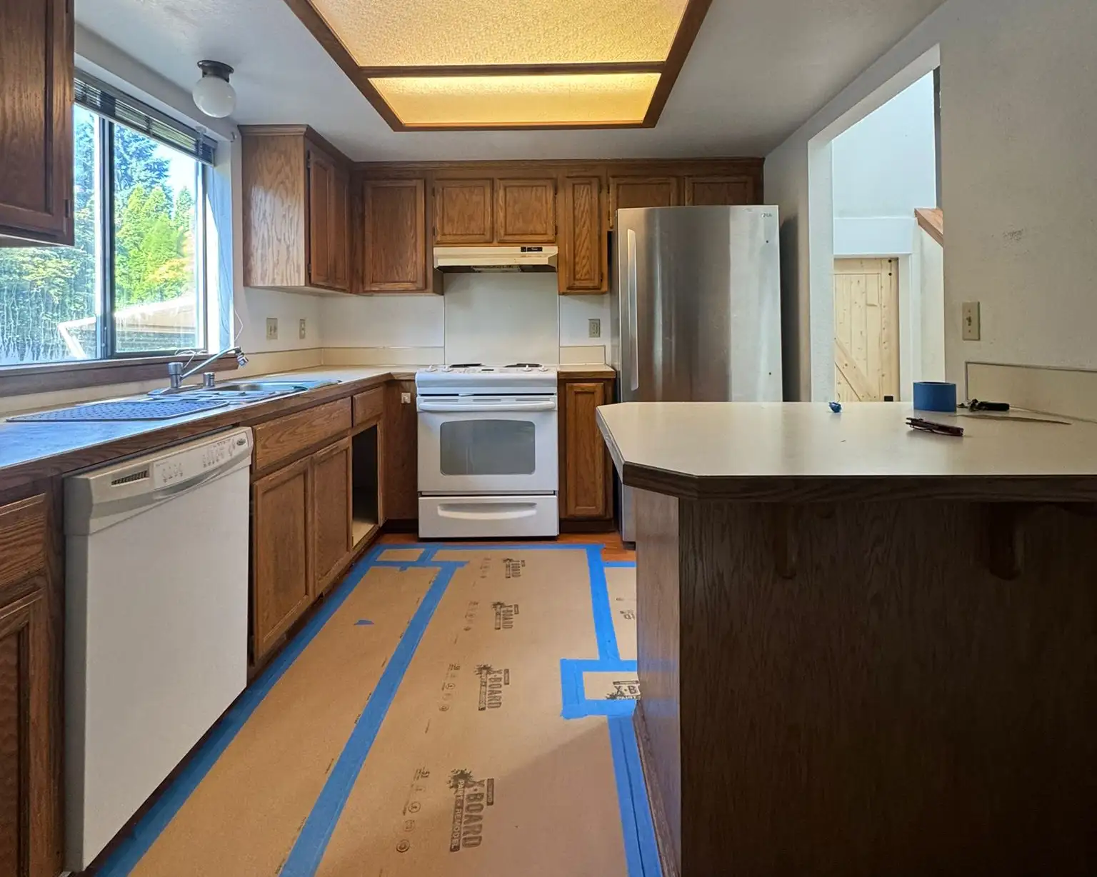 Before kitchen remodel in Puyallup showing soffit, old oak cabinets, and fluorescent ceiling light.