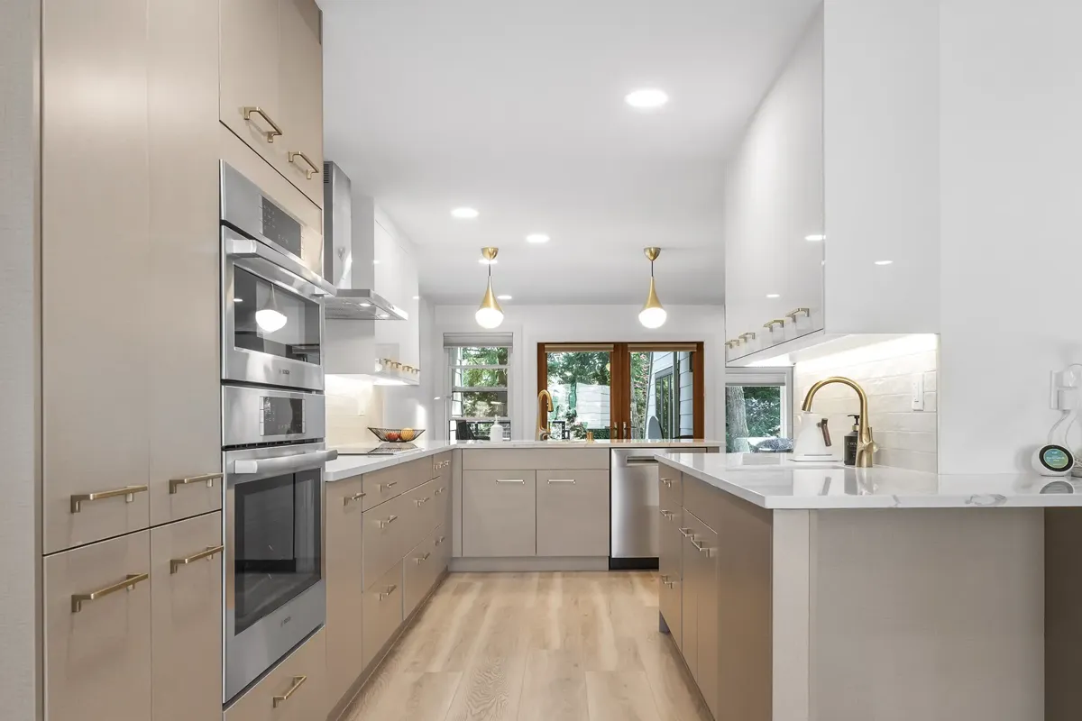 modern kitchen renovation with two tone cabinets quartz countertops and warm wood flooring