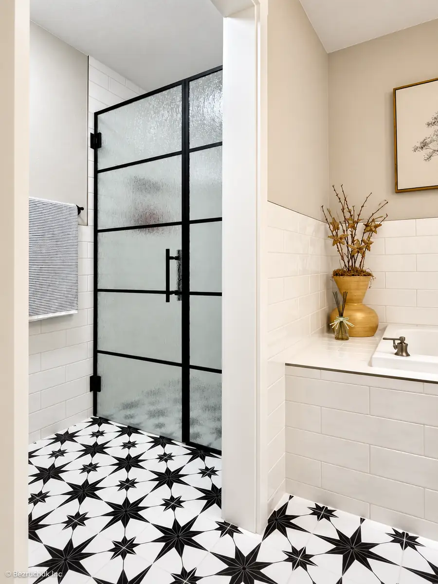Finished black-framed shower enclosure beside white wall tile and star-patterned flooring