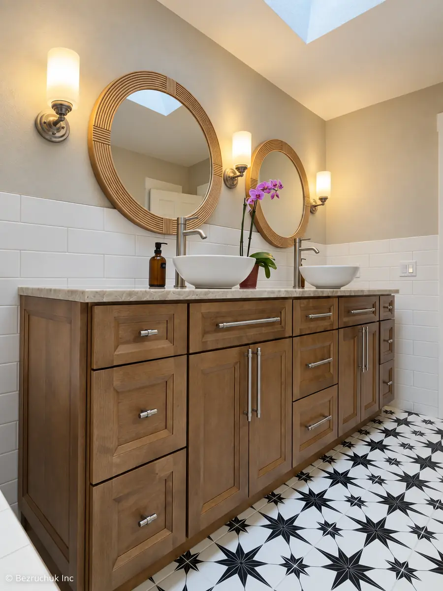 After the South Hill remodel, wood-tone double vanity with vessel sinks and two round mirrors