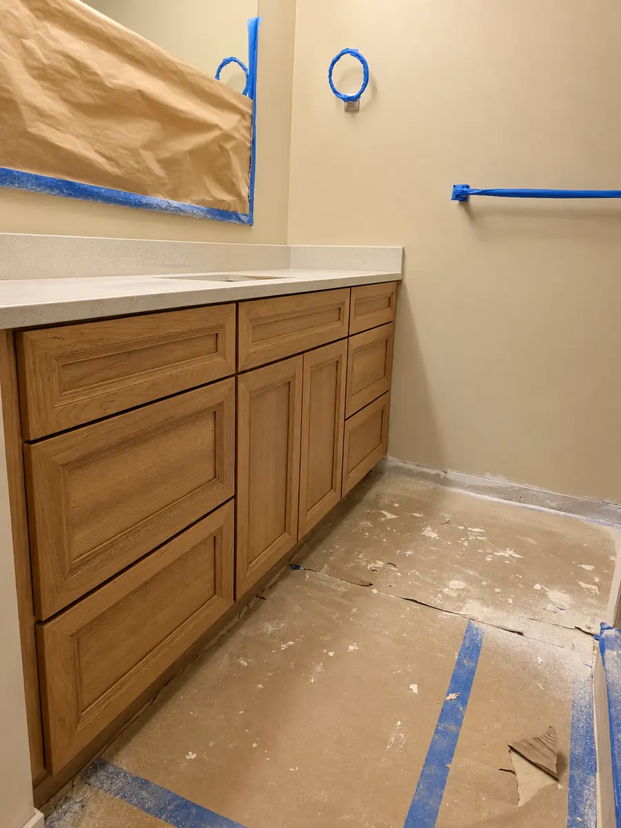 - project image Existing wood vanity during restoration with the mirror masked for painting and the floor protected