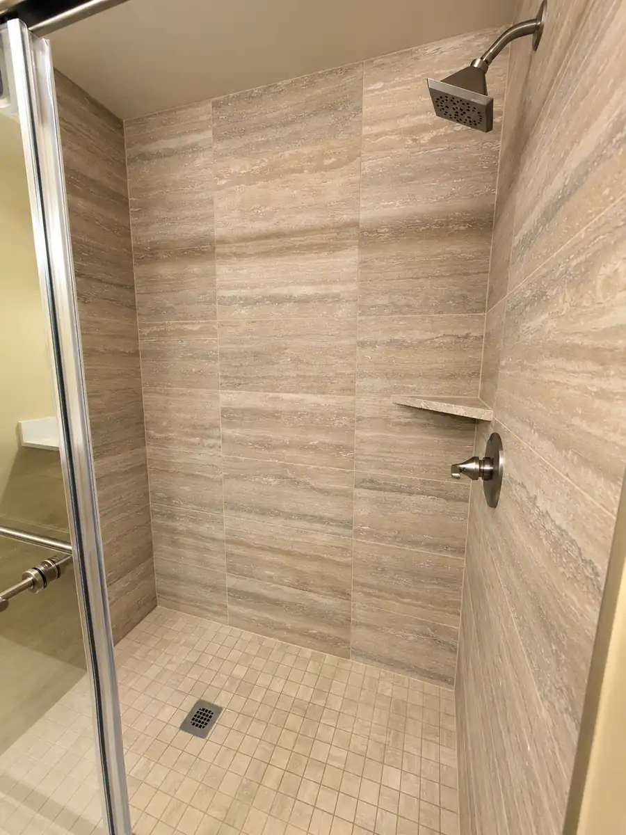 - project image Restored shower with beige veined wall tile and a clear glass enclosure