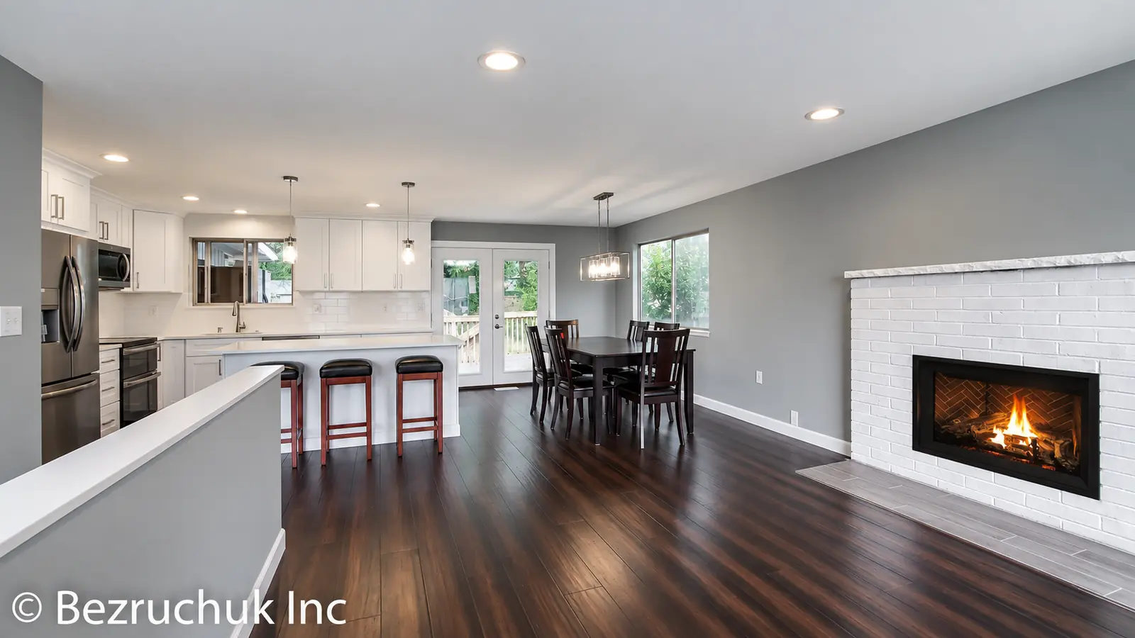 Completed Adelaide kitchen in Federal Way with a white island, dining area and fireplace