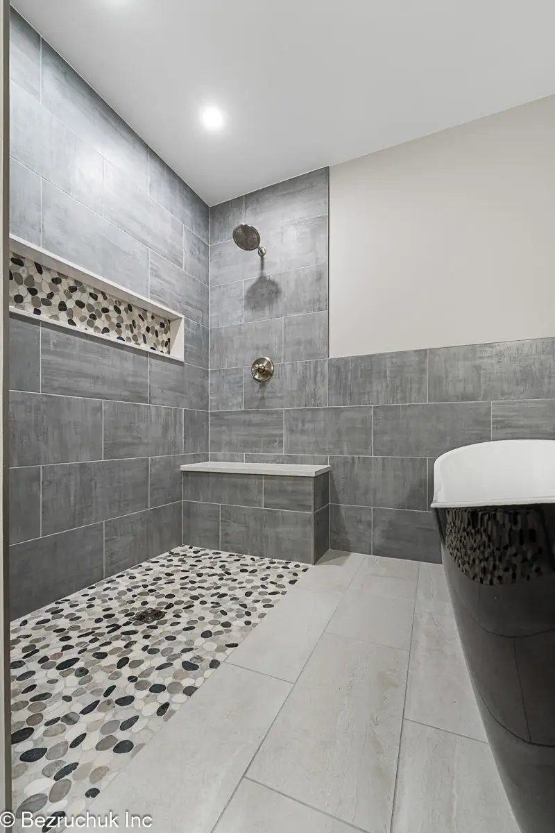 - project image Curbless pebble shower floor beside a black freestanding tub in Graham