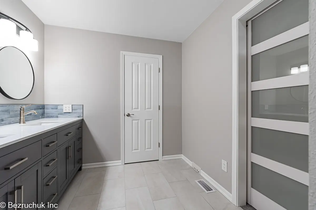 - project image Gray bathroom vanity beside a white door with frosted glass panels