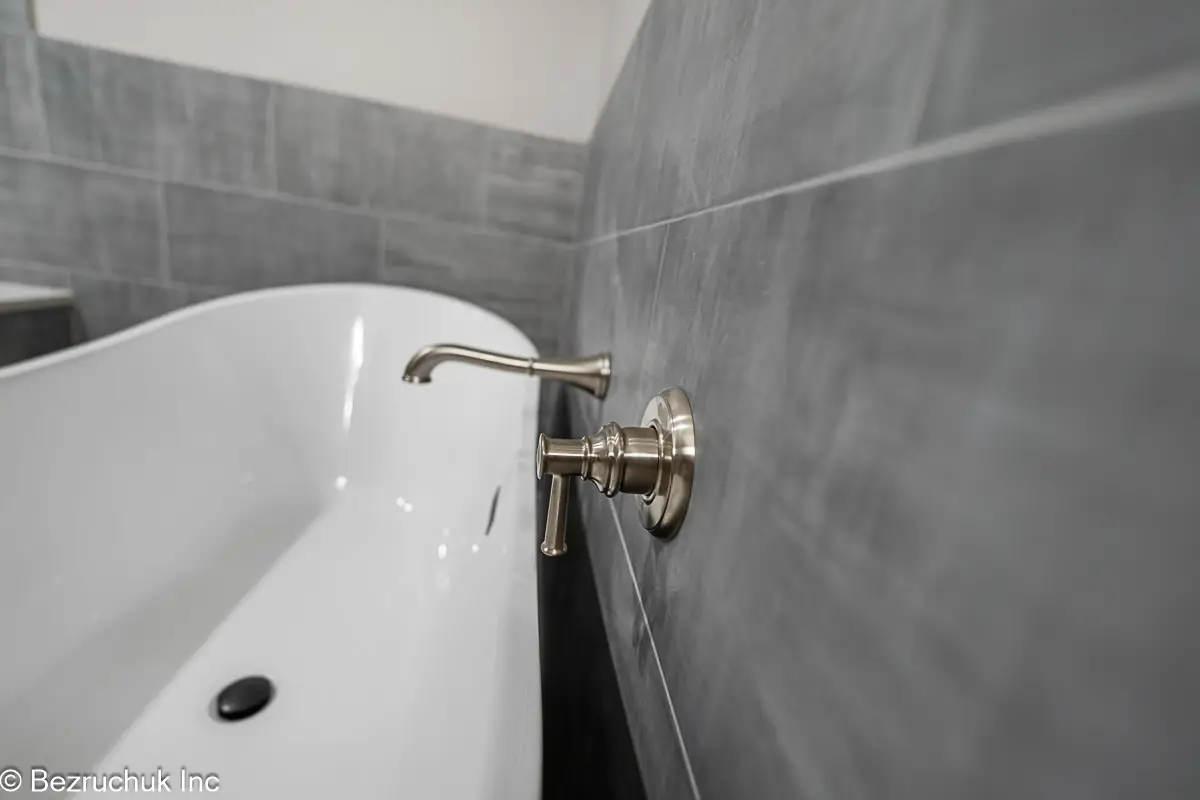 - project image Wall-mounted tub filler over the white interior of a black freestanding tub