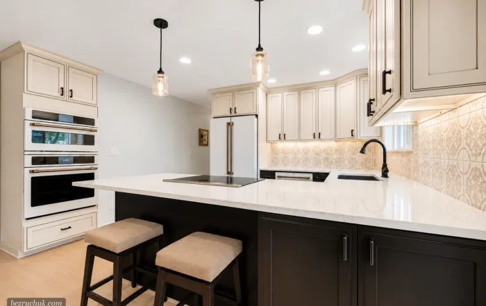 - project image Finished Puyallup kitchen island with dark cabinets, light countertop, induction-style cooktop, stools, and wall ovens