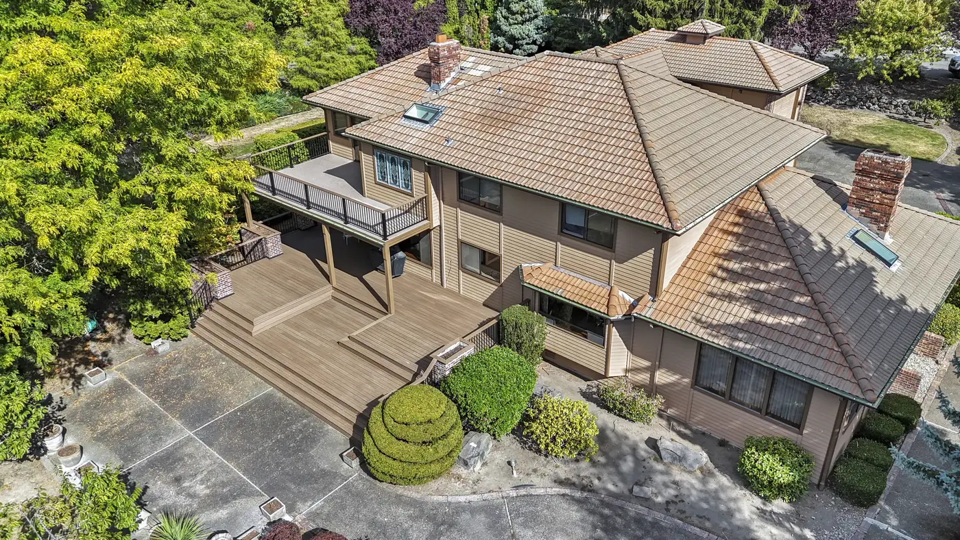 Aerial view of a large multi-level deck with wide stairs and an upper balcony deck with dark metal railing