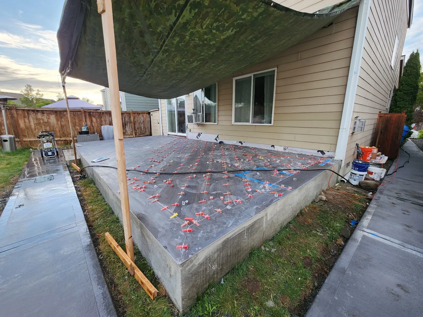 - project image Porcelain planks being installed on the concrete deck with red and white leveling clips.