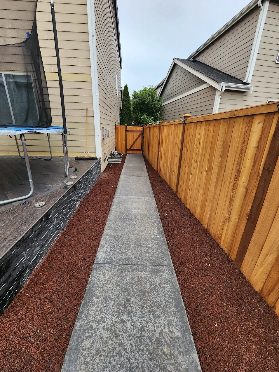- project image Concrete side path runs between the cedar fence and the slate-clad edge of the tile deck.