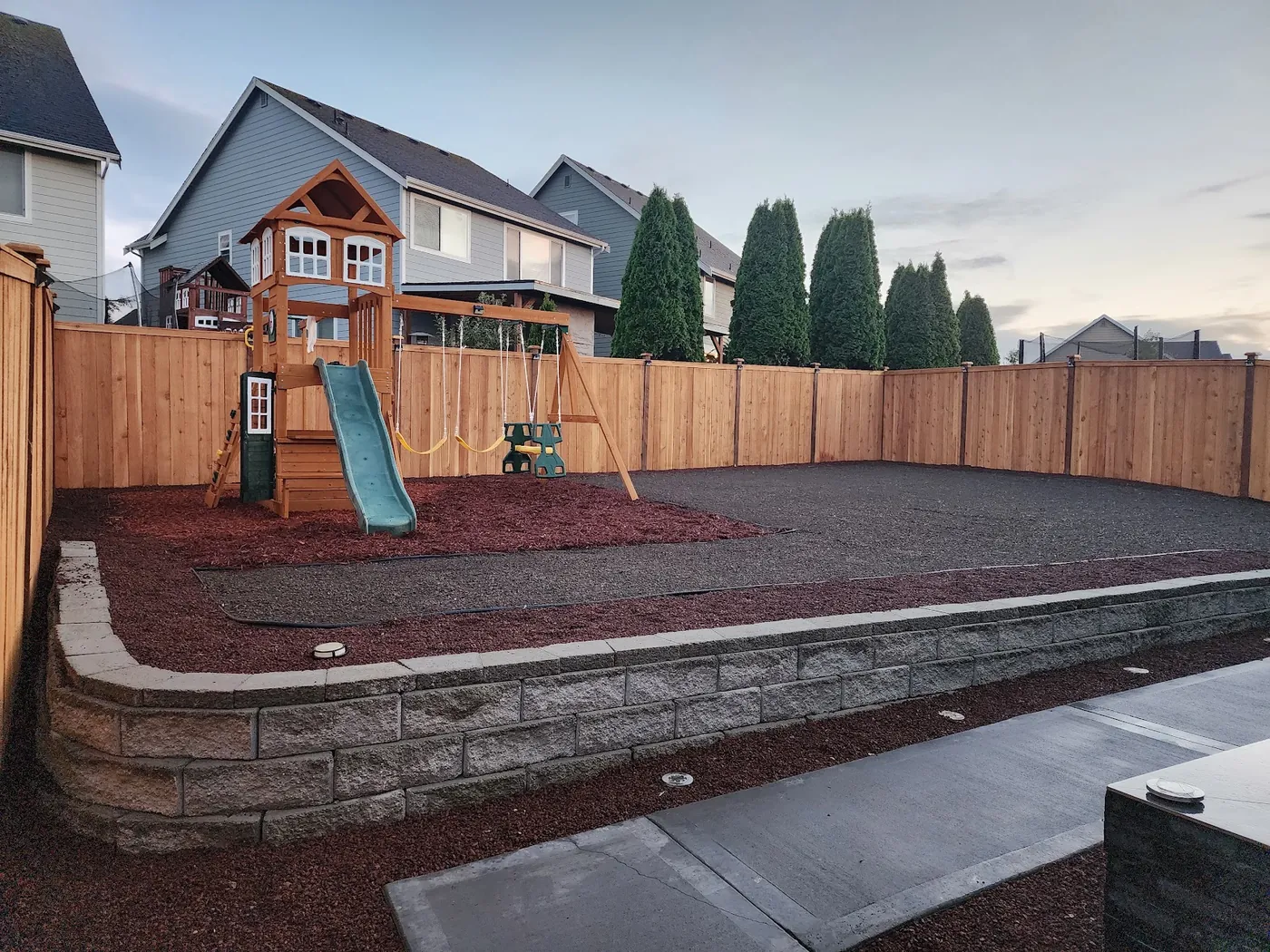 - project image Block retaining wall and fenced play area during yard work, before the lawn shown in the finished views.